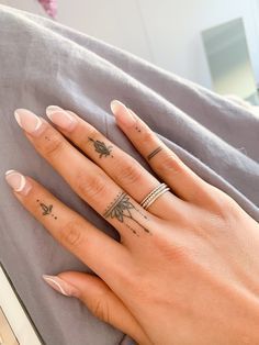 Small Hand Tattoos7 Close-up of a hand with rings and small intricate finger tattoos, resting on a grey fabric background. | Sky Rye Design Girly Hand Tattoos, Hand Tattoo Ideas, Side Hand Tattoos, Love Yourself Tattoo, Nurse Tattoo, Power Tattoo, Taurus Tattoos, More Tattoo, Simple Tattoo Designs