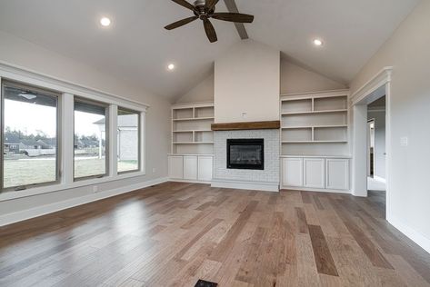 Spacious, open living space with vaulted ceilings and a custom fireplace with built-in shelving. Fit to suit all types of decor, boho, modern, classic, modern farmhouse, and more! Unique living room details #interior #discoverybuilders #livingroom #familyroom #livingroominspo #openconcept #livingroomflooring #lightfixtures #newconstruction #modernfarmhouse #buildinginspo #discoverthedifference #rustic #decorating Living Rooms Vaulted Ceilings, Vaulted Ceiling With Built Ins, Diy Built Ins Around Fireplace Vaulted Ceiling, Vaulted Ceiling Living Room No Beams, Fireplace That Doesnt Go To Ceiling, Built In Shelves Living Room Fireplace Vaulted Ceiling, Vault Ceiling Fireplace, Living Room Built Ins With Vaulted Ceiling, Built In Entertainment Center Vaulted Ceiling