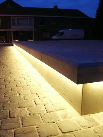 Urbastyle provided benches with integral LED strip lighting for Balgerhoeke village square near Ghent in Belgium. By day, the square is bordered with concrete benches while, by night, the integrated lighting highlights the architectural reliefs and illuminates the space... Bench Lighting, Concrete Benches, Handrail Lighting, Lighting Architecture, Exterior Lighting Design, Lighting Exterior, Lighting Design Inspiration, Village Square, Led Profile