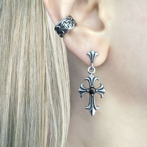 Gothic Cross Earring, a striking piece of jewelry that embodies the essence of gothic style and dark elegance. Crafted with meticulous attention to detail, this earring is designed to make a bold statement and add a touch of mystique to any outfit. Sold as Single or Pair Material : 316 Stainless steel Set with Black and Clear Cubic Zirconia Size: 38 mm long Closure: Butterfly push back Listing for pair of earrings only Spring Goth Earrings, Elegant Gothic Jewelry, Goth Ear Stack, Elegant Piercings, Moodboard Jewelry, Gothic Moodboard, Cross Piercing, Alt Earrings, Goth Piercings