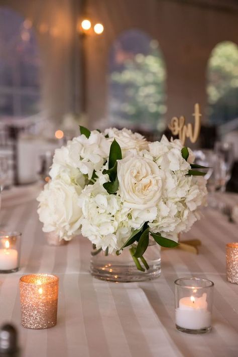 Low White Rose Centerpiece, One Vase Wedding Centerpiece, Small Centerpieces With Candles, Small White Centerpieces Simple, White Rose Bouquet Centerpiece, White Roses In Glass Vase, Hydrangea And White Roses Centerpiece, Simple Hydrangea Centerpiece Wedding, Round Flower Centerpieces