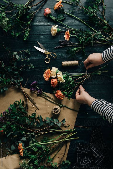 Unknown woman working at florist desk arranging flowers in order to create a bouquet by Laura Stolfi for Stocksy United #florist #flower #bouquetinthemaking #flowerbouquet #darkflower #flatlay #flowerflatlay #flowerarrangement #fromabove #workingwoman #table #greenthumb #floristtable #carnation #manyflowers #vintagescissors #yellowandorangeflowers #gerberas Flowers In Bouquet, Flower Flat Lay, Florist Brand, Arranging Flowers, Herbs De Provence, Dark Flowers, Floral Photography, Spices And Herbs, Beautiful Bouquet Of Flowers