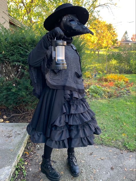 A typical plague doctor costume with a farmer’s hat, a mask with a long beak, long-sleeves tee shirt, a short cape, leather gloves, a (not typical) Lolita-style midi skirt with frills and ruffles, tights, and combat boots. Plague Doctor Inspired Outfits, Plague Doctor Woman, Crow Mask Plague Doctor, Plague Nurse Costume, Female Plague Doctor Costume, Plague Doctor Costume Women, Magpie Costume, Plague Doctor Female, Witch Doctor Mask