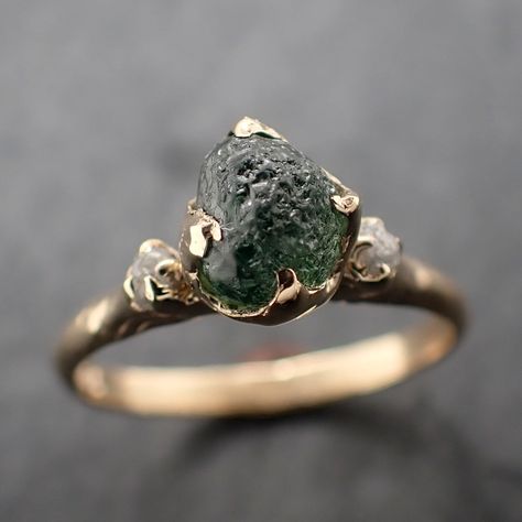 Raw rough green Montana sapphire surrounded by two raw conflict-free diamonds. I hand carved this ring in wax and cast it in solid 14k yellow gold using the lost wax casting process. This one of a kind raw gemstone ring is a size 7 it can be resized up or down. The sapphire stone measures about 6.5 x 5.5mm. The rough diamonds are about 2mm. The band is around 2mm. Throughout all time and history in every tribe and culture all around the world crystals, minerals and gemstones have used for healin Raw Stone Wedding Ring, Raw Moss Agate Ring, Natural Rock Ring, Raw Sapphire Jewelry, Uncut Gem Ring, Moldavite Wedding Ring, Rough Emerald Ring, Gold Band Green Stone Engagement Ring, Precious Stone Ring