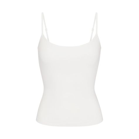 A classic cami in the internet’s favorite lounge fabric. This ultra-comfy top is made with our addictively soft, slinky ribbed fabric for flattering comfort on the couch or on the go. Features an interior shelf bra with underbust elastic for light bust support, a chic scoop neck, and adjustable back straps. Hits below the natural waist and fits true to size. Given the semi-sheer nature of this colorway, we recommend wearing with a SKIMS foundation in your go-to neutral shade. Neutral Tank Tops, Simple White Top, Fame Clothes, White Spaghetti Strap Top, White Cami Top, Basic Clothes, White Cami Tops, At Home Outfits, White Tube Top