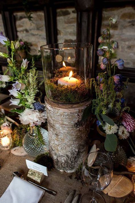 a woodland wedding centerpiece of bold blooms, greenery, moss and a tree stump with a candle and moss Green Moss Wedding Decor, Moss And Roses Centerpieces, Small Enchanted Forest Wedding, Moss And Wood Table Decor, Mossy Wedding Bouquet, Woodland Themed Wedding Decorations, Spanish Moss Wedding Centerpiece, Moss Party Decor, Mossy Centerpieces