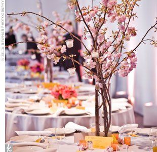 Bright bursts of orange and pink punched up the tables. The couple used sprigs of cherry blossom for their tall arrangements and clusters of peonies, tulips, sweet peas and freesia for the shorter centerpieces. Cherry Blossom Wedding Decor, Cherry Blossom Centerpiece, Branch Centerpieces Wedding, Tree Wedding Centerpieces, Cherry Blossom Wedding Theme, Cherry Blossom Theme, Wedding Themes Spring, Cherry Blossom Wedding, Japanese Wedding