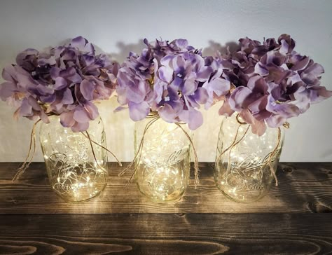 "Set of 3 Fairy Lit Mason Jars With Optional Hydrangea Heads For Wedding and Home Decor This beautiful set of 3 fairy lit mason jars will make a wonderful accent to any country, farmhouse or rustic style decor. Available in 2 different sizes, 11 different color options, and with or without hydrangeas you can easily customize your order to fit your homes decor. These fairy jars look so pretty lit up and are perfect to use as wedding and event table decor, or in the living room, dining room, bedro Mason Jar Decorating Ideas, Pooh Wedding, Quinceanera Checklist, Mason Jars With Lights, Fairy Lights In A Jar, Rustic Style Decor, Table Decor Wedding, Elegant Wedding Centerpiece, Farmhouse Table Decor