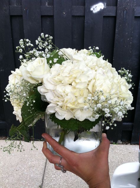 white hydrangea, white rose, and babysbreath centerpiece in clear glass cube (wedding) Hydrangea Simple Centerpiece, Hydrangea White Centerpiece, Inexpensive Floral Centerpieces Simple, Hydrangea Centre Pieces, Green And White Hydrangea Centerpiece, Wedding Decor Hydrangea, Hydrangea And Baby Breath Arrangements, Unique Floral Centerpieces, Wedding Centerpieces Babysbreath