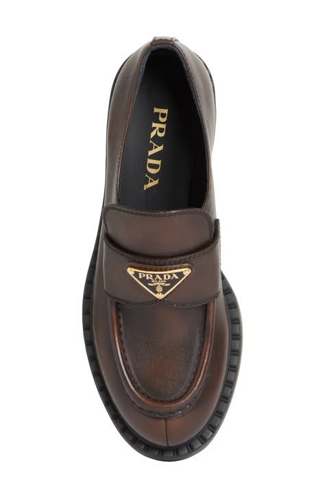 The Prada emblem marks the band of this classic moc-toe loafer lifted on a thick rubber sole and crafted from chocolatey burnished leather. 1 3/4" (50mm) heel Leather upper and lining/rubber sole Designer Shoes Brown Prada Loafers, Womens Loafers Outfit, Prada Loafers Women Outfit, Prada Loafers, Loafers Women, Loafer Women, Street Fashion Men Streetwear, Prada Shoes, The Band