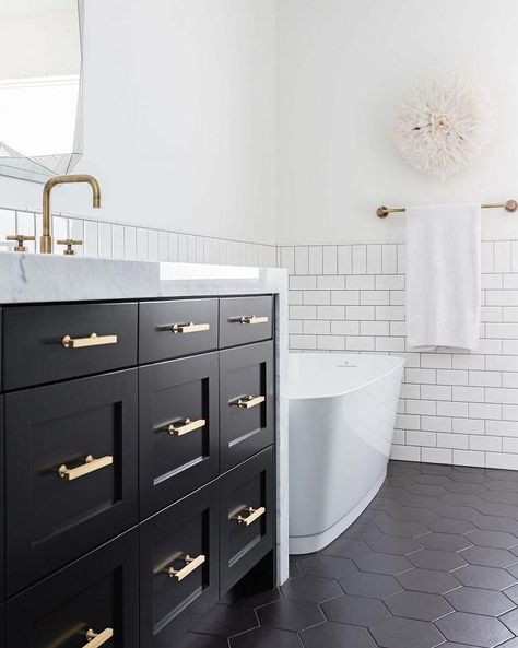 Black hexagon floor tiles in a transitional bathroom designed with a black shaker washstand, brass pulls and a thick marble countertop. Black Hexagon Tile Bathroom, Black Hexagon Floor, Hexagon Tile Bathroom, Transitional Bathroom Design, Black White Bathroom, Black Tile Bathrooms, Gramercy Park Hotel, Hexagon Floor, Black And White Bathroom