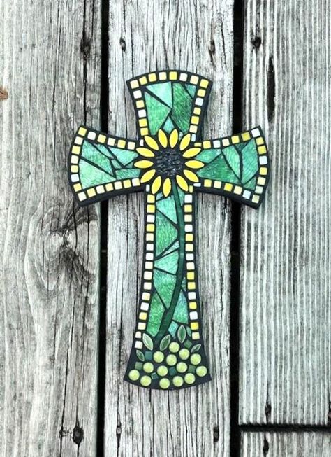 This original design mosaic cross made on sturdy MDF board, is 13" tall and would look gorgeous hanging on your wall! The flower design is done with a combination of ceramic petals and stained glass stems, all sprouting from the pale green glass gems. The bright yellow sunflower really stands out against the beautiful wispy light green textured stained glass background, edged in various shades of tiny yellow glass tiles. The cross is painted black on the sides and back, is grouted in black, whic