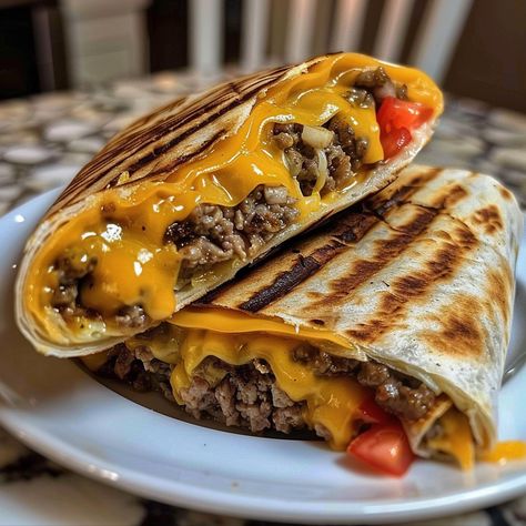 The Grilled Cheeseburger Wrap combines the classic flavors of a cheeseburger with the convenience of a wrap. It's a perfect fusion of two beloved dishes, offering a delightful twist on traditional fast food. This dish is not only easy to make but also customizable, allowing you to add your favorite toppings and sauces to suit...Read More Cheese Burger Wraps Ground Beef, Grilled Cheese Burger Wraps, Hamburger Wrap Recipes, Cheeseburger Crunch Wrap Recipe, Cheese Burger Tortilla Wraps, Hamburger Sandwich Ideas, Wrap Burger Recipes, Tortilla Wrap Ideas Healthy, Grilled Cheeseburger Wraps