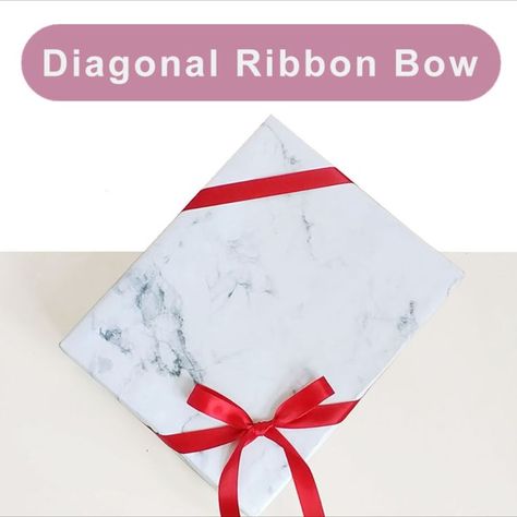 Tying diagonal ribbon bow around gift wrapping box Diagonal Ribbon On Gift, Ribbon On Presents, Tie Bows With Ribbon, Christmas Present Ribbon, How To Wrap Presents, Bows For Presents, Diy Gift Bow, Wrapping Ribbon, Present Box