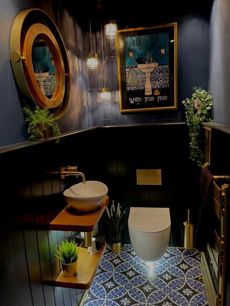 Downstairs cloakroom with wall hung toilet and sink. Victorian style floor sets off the lower tongue and groove boarding painted in F&B Railings and the upper wall and ceiling painted in F&B Stiffkey Blue. Brushed gold flush plate, taps and accessories add to the glamorous feel. Warm oak floating shelves, plants,  and a vintage style poster in a gold frame soften the look. A cascading chandelier, low power spot lights and lighting under the loo and sink shelves provide plenty of warm light Industrial Bathroom Ideas, Small Downstairs Toilet, Bathroom Ideas On A Budget, Bathroom Ideas Small, Downstairs Toilet, Industrial Bathroom, Small Bathroom Makeover, Small Bathroom Ideas On A Budget, Small Bathroom Ideas Modern