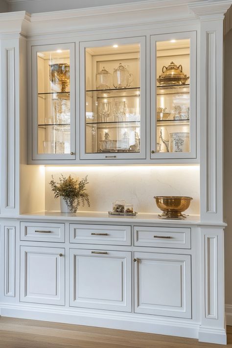 Elegant white kitchen cabinet displaying glassware and silverware with built-in lighting.