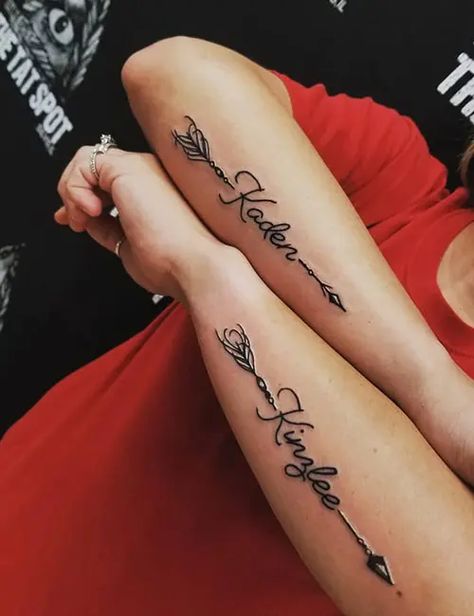 Name Tattoo Feminine, Flower With 2 Name Tattoo, Arm Tattoos For Women Sons Name, Arrow With Name Tattoo Design, Name Tattoo Forearm Woman, Name Shoulder Tattoos For Women, Couples Names Tattoos, Men’s Name Tattoos, Tatoos Woman Hand Name