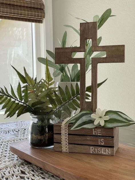 I've created a couple Easter crafts this year, but this one is my favorite because it focuses on the true meaning behind this special season! I'm have various book stacks in my home also, but this was my first time creating a "faux" stack using a crate instead of actual books. I loved the result! Dollar Tree has these wood crate and cross forms. Grab one of each and paint or stain in your favorite finish. Next we are going to add "He Is Risen" to one side of the crate. You can cu… Easter Book, Easter Books, Church Easter Decorations, Easter Cross, Christian Decor, Easter Centerpieces, Spring Easter Decor, Wooden Cross, Rustic Garden Decor