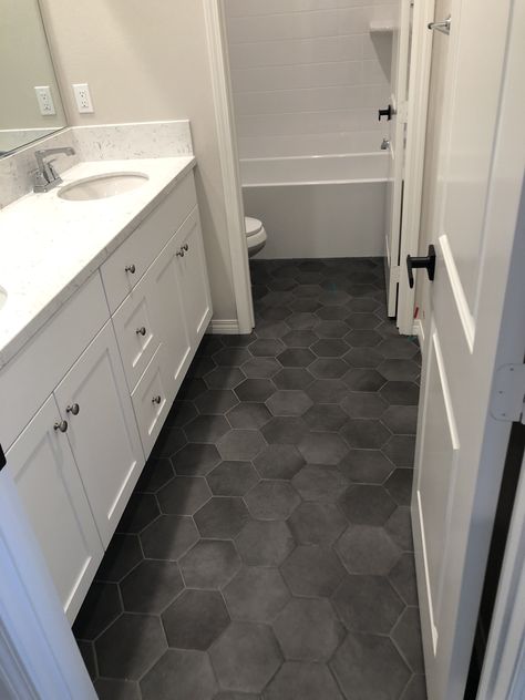 Black Tile Floor Master Bath, Grey Tile Floor Bathroom Ideas, White Vanity Black Floor, Charcoal Hexagon Tile Bathroom Floor, Bathroom Hex Tile Floor, Dark Grey Hex Tile Bathroom Floor, Dark Bathroom Floor Tile White Cabinets, Grey Hex Tile Bathroom Floor, Bathroom Dark Floor Tiles