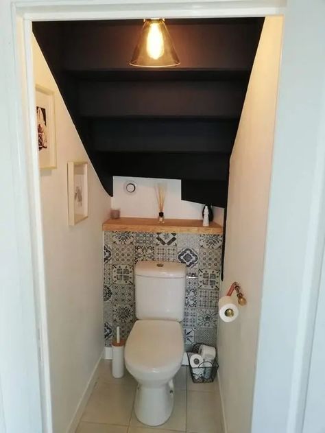 a small powder room under the stairs with a bold tile, a wooden shelf, some decor and a pendant lamp is a cool soluton for a tiny space Understairs Bathroom Downstairs Toilet, Small Understairs Bathroom, Half Bathroom Ideas Under Stairs, Under Stairs Wc, Wc Under Stairs, Toilet Under Stairs Ideas, Half Bath Under Staircase, Under Stair Toilet, Small Bathroom Under Stairs