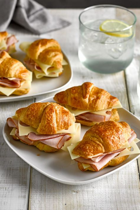 A plate with croissants filled with sliced ham and cheese on a table. Meat And Cheese Croissant, Costco Croissants Sandwiches, Ham Cheese Croissant Sandwiches, Ham And Cheese Mini Croissant, Ham Swiss Croissant, Mini Croissants Sandwiches, Fillings For Croissants, Mini Ham And Cheese Croissants, Ham And Cheese Crossaints