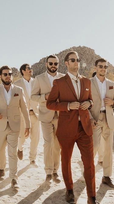 Caramel Groomsmen Suits, Groom Burnt Orange Suit, Colourful Groomsmen Attire, Colored Grooms Suits, Peach Wedding Theme Groomsmen, Wedding Party Sunset Colors, Rust Colored Suit Wedding, Sage Green And Burnt Orange Groomsmen, Burnt Orange Weddings Groomsmen Jeans