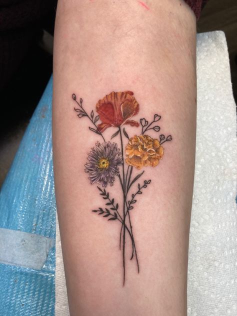 Tattoo of an aster, a poppy, and a marigold on forearm Aster And Cosmos Tattoo, Two Marigold Tattoo, Daisy Rose And Marigold Tattoo, Marigold Rose Tattoo, Poppy Marigold Tattoo, Marigold And Aster Tattoo, Aster And Cosmos Flower Tattoo, Poppy And Cosmos Tattoo, Poppy And Aster Tattoo