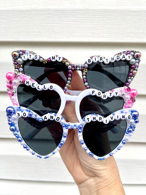 These sunglasses are unique, stylish and just the perfect gift! The heart-shaped design makes them so cute and trendy.  If you would like them customized just message me.  Possible options you might like: hello forty, fifty and fab, 21 and fun, newly 21, 30 and flirty, birthday queen, birthday babe, birthday gal, this is 40, 21 and thirsty, cheers to 21 years, etc. Check the images to see other possible sayings or you can always create your own.  Return Policy: As these sunglasses are customized products, we do not accept returns or exchanges unless there is a misspelling, we will send a corrected item at no additional charge. Bedazzled Sunglasses, Hello Forty, Birthday Sunglasses, Diy Jar, Rave Fits, Birthday Accessories, Birthday Babe, Custom Birthday Gifts, Queen Birthday