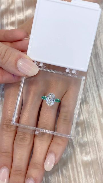 Lauren B on Instagram: "Watch this breathtaking three-stone ring pop to life! 💎 Gorgeous oval diamond featuring green emerald pear shaped side stones - would you say “I DO” to this stunner? 😍🤩 Based on 💍 ring style RS-329 #laurenb #laurenbjewelry #ovaldiamond #ovalring #ringinspo"