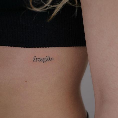 fragile tiny tattoo on rib feminine Most Feminine Tattoo Placement, Fragile Word Tattoo, Dainty Rib Cage Tattoos, Fragile Tattoo Words, Placements For Small Tattoos, Tattoo Placements For Women, Dainty Rib Tattoos For Women, Rippen Tattoo Frau, Fragile Tattoo