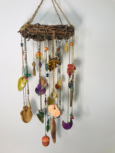 Discover a harmonious blend of nature and artistry with this unique wind chime. Crafted with handmade ceramic leaves and adorned with beads and repurposed jewelry for a touch of sparkle, this piece is a nature lover's treasure.  Suspended from a natural grapevine wreath, on which I've attached a small grapevine heart in the center, it creates a gentle tinkling sound as a breeze catches its charms, but no breeze is necessary to appreciate the details! Ideal for indoor or covered outdoor spaces enjoy the fall (or any season) looking at this pretty piece on your porch, sunroom, kitchen ceiling or any favorite sitting area.  Each piece on the wind chime has been attached with attention to detail-you'll find hand painted wooden acorns, beads, metal celestial shapes, and handmade ceramic leaves, Driftwood Mobile Wind Chimes, Crafts With Nature, September Crafts For Seniors, Fall Paper Garland, Wall Decor With Paper, Rustic Wind Chimes, Wooden Acorns, Driftwood Wind Chime, Windchimes Diy