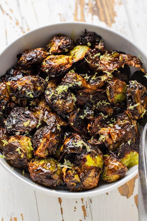 These crispy roasted restaurant-style brussels sprouts have quickly become our favorite way to prepare brussels sprouts. These brussels are halved and roasted cut side down on a hot baking sheet until they're golden brown and ultra tender. While you can certainly eat them as is, they're finished with a drizzle of balsamic glaze, honey, and freshly zested lemon. #brusselsprouts #roastedveggies Sticky Brussel Sprouts, Crispy Asian Brussel Sprouts, Roasted Brussel Sprouts Oven Crispy, Restaurant Style Crispy Brussel Sprouts, Ways To Make Brussel Sprouts, Fancy Brussel Sprout Recipes, Brussel Sprout Recipes Lemon, Crispy Oven Roasted Brussel Sprouts, Best Roasted Brussels Sprouts