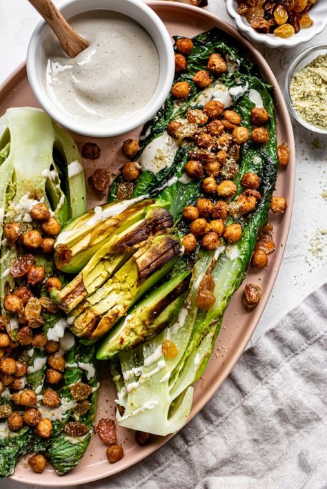 This Grilled Romaine Salad with Tandoori Chickpeas and Golden Raisins is made with crispy grilled romaine hearts topped with grilled avocado, roasted tandoori chickpeas, golden raisins, vegan parmesan cheese, and a creamy tahini dressing! This vegan grilled salad is perfect as an appetizer or as a lunch all on its own! Vegan Cesar, Grilled Romaine Hearts, Chickpea Croutons, Virtual Friend, Romaine Hearts, Grilled Romaine Salad, Grilled Vegetable Recipes, Grilled Salad, Grilled Romaine