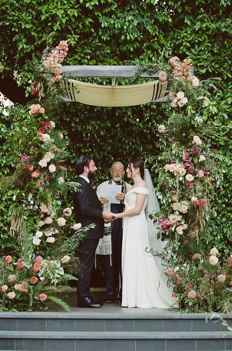 Bride and Groom hold hands under a gorgeous summer garden chuppah at Four Seasons Beverly Hills. Their Rabbi is draped with a Talit as he reads from his script. Green Chuppah, Wildflower Aisle, Chuppah Wedding, Purple Napkins, Candles Purple, Aisle Arrangements, Chuppah Ideas, Jewish Wedding Ceremony, Ceremony Aisle