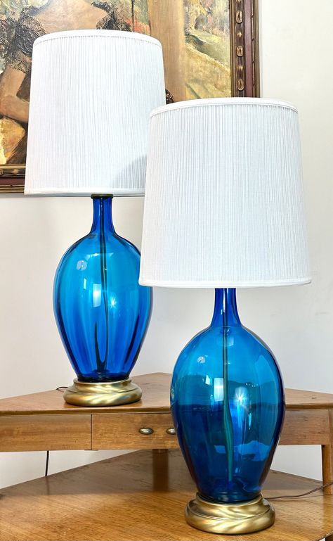 Introducing a dazzling set of 2 Large Blue Blenko Table Lamps That will embellish your home decor to new heights of beauty and taste. These vibrant lamps stand at an impressive 36 inches tall with shades, casting a warm, ambient glow throughout your space, while the exquisite Blenko glass design adds depth and visual intrigue. The rich, vibrant blue hue emanates a lively charm and perfectly complements the captivating Blenko aesthetic. Each lamp features a stunning glass base, measuring 22 inche Blenko Glass, Blue Glassware, Large Table Lamps, Blown Glass Art, Mid Century Ceramics, Cute Room Decor, Unique Lamps, Large Table, Vibrant Blue