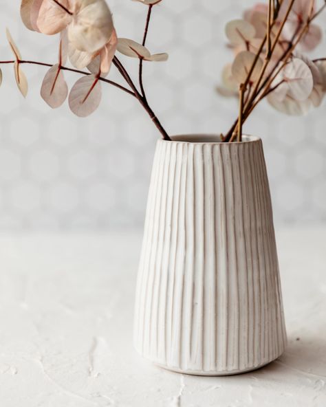 Our tall fluted vase is great for a large bunch of flowers, its textural design adds visual interest while still creating the perfect neutral backdrop to your flower arrangement.It is wheelthrown using Stoneware clay, then handcarved and glazed in white.It measures approx 17.5 cm high x 8.5 cm at t Clay Flower Pots Diy, White Pottery Vase, Tall Pottery Vases, Ceramic Pottery Vase Ideas, Cute Pottery Vase, Vase From Clay, Beginner Pottery Vase, Textured Ceramic Vase, Vase Clay Ideas