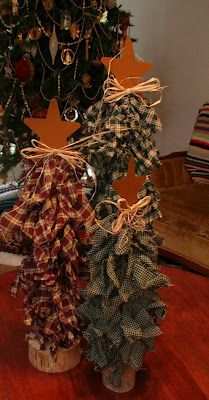 DIY Rag Trees - these are made out of dowels to desired length, and torn home spun fabric in Christmas colors, a rusty tin star, raffia, and a piece of branch that has been cut on a band saw and drilled in the middle to accommodate dowel. Natal Country, Boom Kunst, Fabric Christmas Trees, Prim Christmas, 12 December, Primitive Crafts, Primitive Christmas, Country Christmas, Christmas Deco