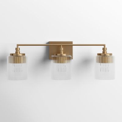 Striking lines and pronounced details create this 3-light vanity. The finish adds a hint of glamour to the modern frame and clear glass cylinders. The Adalina three-light vanity fixture provides abundant light for your bath vanity while adding a layer of today's style to your interior design. Joss & Main Finish: Satin Brass | Joss & Main Adalina 3 - Light Dimmable Vanity Light 8.75 H x 22.63 W x 6.34 D in pink / yellow, Glass in Satin Brass | 8.75" H X 28" W X 6.34" D | Wayfair Mediterranean Bathroom Lighting, Gold Bathroom Light Fixtures, Brass Vanity Light, Bronze Bathroom, Vanity Light Fixtures, Brass Bathroom, Downstairs Bathroom, Gold Bathroom, Powder Bath