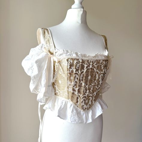 Handmade corset / stays made from a gold and ivory brocade, with coutil interlining, and a satin lining, and gold eyelets. The stays are finished with extreme care to detail with ribbon lacing, metal eyelets, and cotton binding. Fully boned with 19 pieces of plastic boning. Size is around a Small - flexible due to the lace up back. The mannequin it's shown on is a 32" bust and a 26" waist, and flat lay measurements when completely closed (so the smallest size I'd recommend it for) is 15" across Rococo Clothing, Rococo Fashion 18th Century, Corset Stays, Pirate Corset, Handmade Corset, Brocade Corset, Gold Corset, Pirate Dress, Rococo Fashion