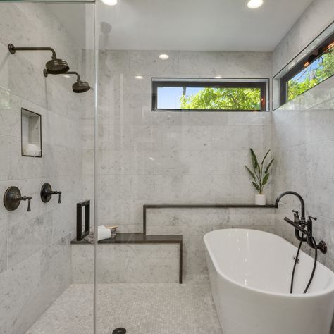 There's so much to love about this bathroom. Placing the bathtub inside the shower is a stylish space saver that also waterproofs the whole bathroom. Double shower heads make this an easy space to share. The cool stone is a perfect touch with a natural looking bench built in. Natural light from the clerestory windows keeps the space feeling bright and open while maintaining privacy. And last but not least, industrial accents add the perfect amount of modern edge! #kelleydesigngroup #bathroom Shower In Tub Combo, Modern Shower Tub Combo Master Bath, Bathroom With Bathtub And Shower Layout, Big Bathtub Shower Combo, Shower Bathtub Combo Layout, Walkin Shower With Bathtub, Soaker Tub Shower Combo Small Bathrooms, Master Bath Tub Shower Combo, Bath Tub Inside Shower Area