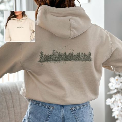 Stay cozy in our "Outsider" sweatshirt, featuring a graphic of a pine tree forest. This nature-inspired wilderness shirt is perfect for granola girls, nature lovers, and anyone who enjoys camping and hiking adventures. NOTE: ALL HOODIES ARE FRONT AND BACK. Prefer this design on a T-Shirt? Visit this link: https://bohemianbloomdesigns.etsy.com/listing/1764509611 Everything You Need to Know: 🧥 Sweatshirt Brand Gildan | Unisex Adult Sizing | 50% Cotton, 50% Polyester ⏳🚚 Production & Shipping All Graphic Hoodie Design Inspiration, Granola Shirts, Nature Shirt Design, Nature Sweater, Granola Vibes, 2024 Clothes, Pine Tree Forest, Clothing Board, Hiking Adventures