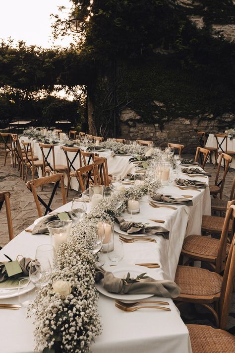 Winding reception tables covered in white tablecloths complete with babys breath table runner and fabric napkins Outdoor Table Decor Wedding, Table Flower Runner Wedding, Wedding Table With White Tablecloth, Baby’s Breath Table Runner Wedding, White Tablecloth Decor, Outdoor Reception Table Decor, Wedding Table Gypsophila, Baby Breath Garland Table, Wedding Table Covers Ideas Tablecloths