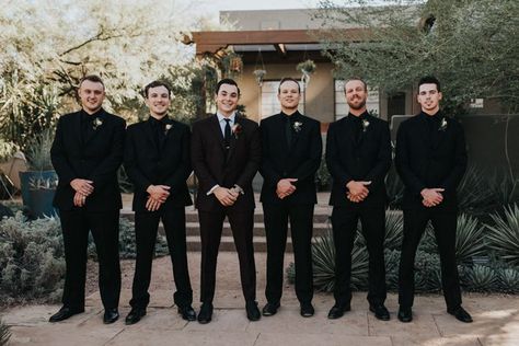 This Black, Burgundy, and Gold Desert Botanical Garden Wedding is a Total Showstopper Gold And Black Groomsmen Attire, Black On Black Mens Wedding Suit, All Black Groomsmen Attire Wedding, Groomsmen All Black Suit, Groomsmen In All Black Suits, All Black Suit Wedding Groomsmen, Fall Wedding Groomsmen Attire Black, Groomsmen Black On Black, Blacked Out Groomsmen