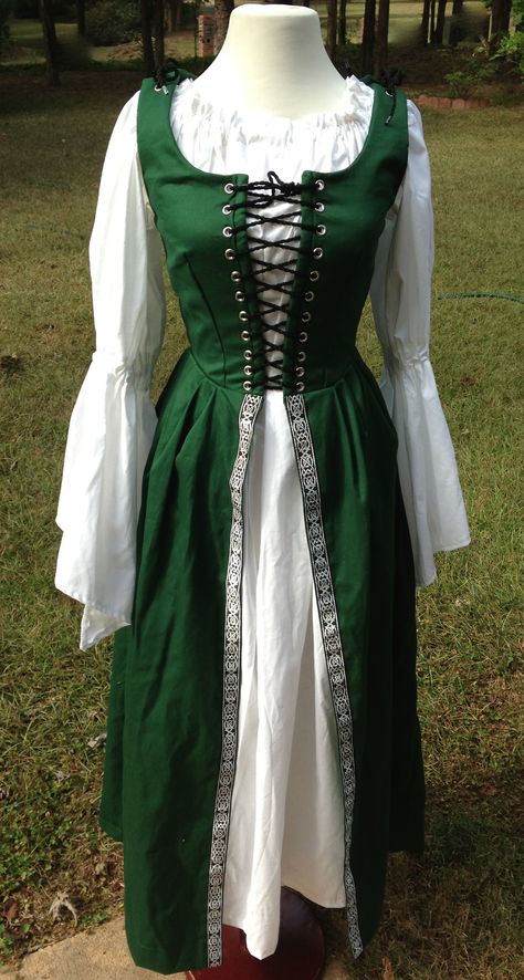 This is one of our Cotton Irish Overdresses with the Celtic Nordic Black and Silver trim added on the skirt. It is machine washable and shown with the white muslin chemise with bell sleeves. Lovely! We also make this is other colors. Irish Traditional Dress, Traditional Irish Clothing, Medieval Costume Women, Celtic Dress, Irish Dress, Pirate Dress, Celtic Clothing, Theater Costumes, Irish Clothing