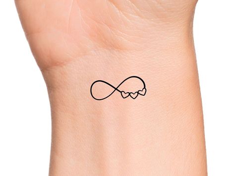 Infinity 3 Hearts Temporary Tattoo Size: The size of this Temporary Tattoo is approximately 1 inch in length. If you would like this design in a smaller or larger size that isn't already listed, please message us directly on Etsy BEFORE placing your order so we can provide you with accurate pricing. Directions: 1. Cut excess paper around tattoo with scissors to eliminate any unnecessary adhesive on your skin after applying. 2. Peel away and discard the clear plastic layer. 3. Apply the tattoo im Fine Line Wedding Band Tattoo, 3 Heart Tattoos For Women, 3 Intertwined Hearts Tattoo, 3 Interlocking Hearts Tattoo, 3 Hearts Tattoo On Wrist, Cute Family Tattoos, Family Related Tattoos, Small Mom Tattoos, Mini Tattoos Family