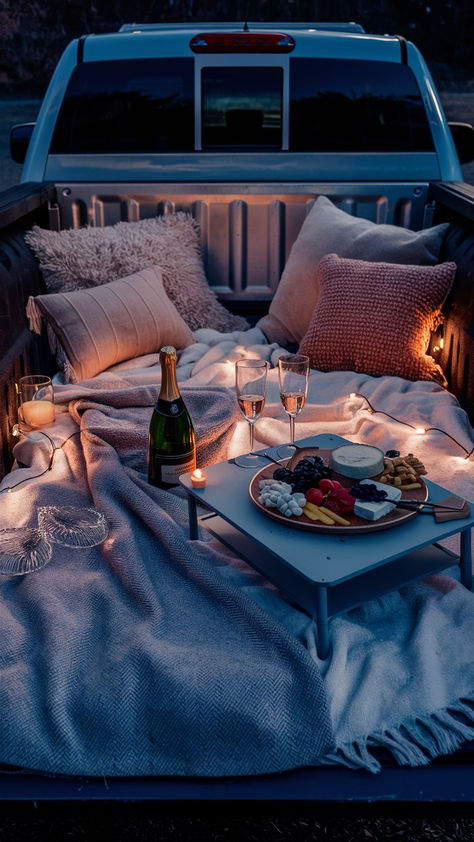 A cozy and romantic truck bed setup with pillows, blankets, candles, fairy lights, champagne, and a charcuterie board. Camping Love Romantic, Date Night Truck Bed, Date Night In The Back Of A Truck, Blanket Fort Date Night Romantic, Tailgate Date Night Trucks Romantic, Truck Dates Under The Stars, Back Of A Truck Date, Pick Up Truck Picnic, Outdoor Movie Night Truck Bed