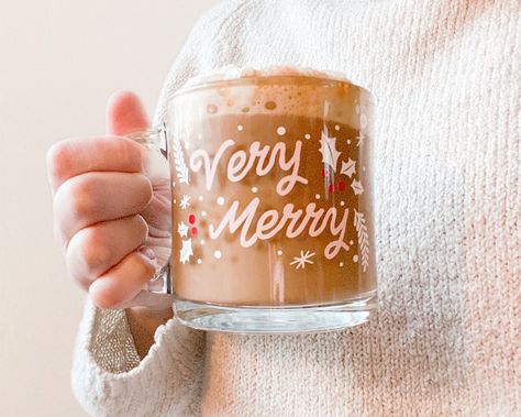 Cozy up by the Christmas tree and enjoy the essence of the holiday season with your favorite festive coffee or hot chocolate! Very Merry Clear Glass mug has a vinyl design hand applied. Festive Christmas mug is the perfect holiday gift!13 oz. clear glass mug with vinyl design applied. Made to order. While the vinyl adhesive is permanent, these mugs are hand wash only. Do not microwave. *Due to the handmade nature of this product, products may vary slightly. Coffee Vinyl Ideas, Clear Mug Cricut Ideas, Holiday Mugs Cricut, Christmas Glass Mugs, Christmas Cricut Mugs, Cricut Christmas Mug Ideas, Christmas Circuit Projects, Cricut Christmas Mugs, Christmas Cricut Cups