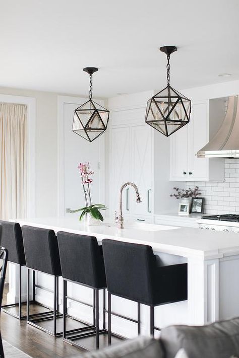 Contemporary white kitchen with black accents is illuminated by two seeded glass polyhedron pendants hung above a white island fitted with a sink and a polished nickel gooseneck faucet fixed to a white quartz countertop seating four black upholstered barstools. Black Bar Stools Kitchen, White Kitchen Bar Stools, Bar Stools For Kitchen Island, Dining Room Island, Bar Stools For Kitchen, Stools For Kitchen, Marble Herringbone, Mosaic Marble, Bar Stools Kitchen Island