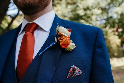 Groom wears a blue suit with orange tie, button hole and pocket square for a colourful and modern wedding at the Royal Welsh College of Music. Photography by Elaine Williams. Navy Blue And Orange Groomsmen Suits, Navy Blue Suit With Rust Tie, Navy Blue Suit Orange Tie, Navy Blue Tuxedo Wedding With Orange, Blue Suit Copper Tie, Blue Suit With Terracotta Tie, Navy Blue Suit With Burnt Orange Tie, Blue Suit With Orange Tie, Navy Blue Tux With Burnt Orange