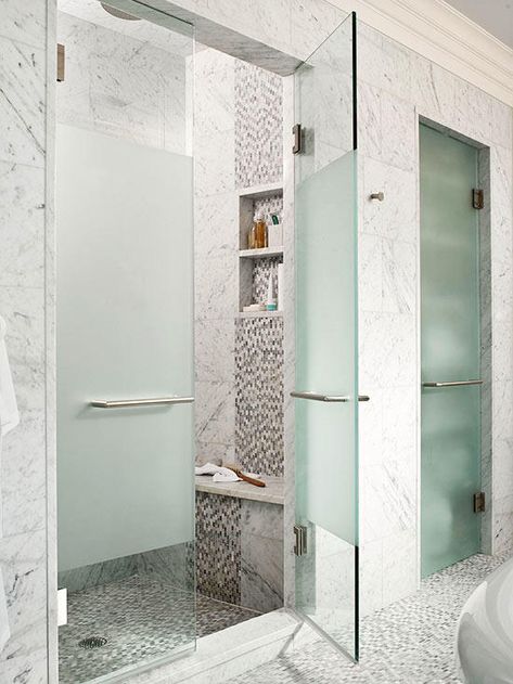 Create a fashionable seat that draws the eye inside your walk-in shower. This shower's interior boasts an arresting interplay of square and mosaic tiles that repeats down the face of the built-in bench, conveniently situated below a pair of toiletry niches. A solid slab of marble overhangs the bench base to magnify the seat's impact. Shower And Water Closet Side By Side, Fogged Shower Door, Fogged Glass Shower Door, Opaque Shower Door Ideas, Walk In Showers With Pony Walls, Opaque Shower Glass, Tinted Shower Glass Doors, Frosted Glass Shower Door Walk In, Opaque Shower Doors